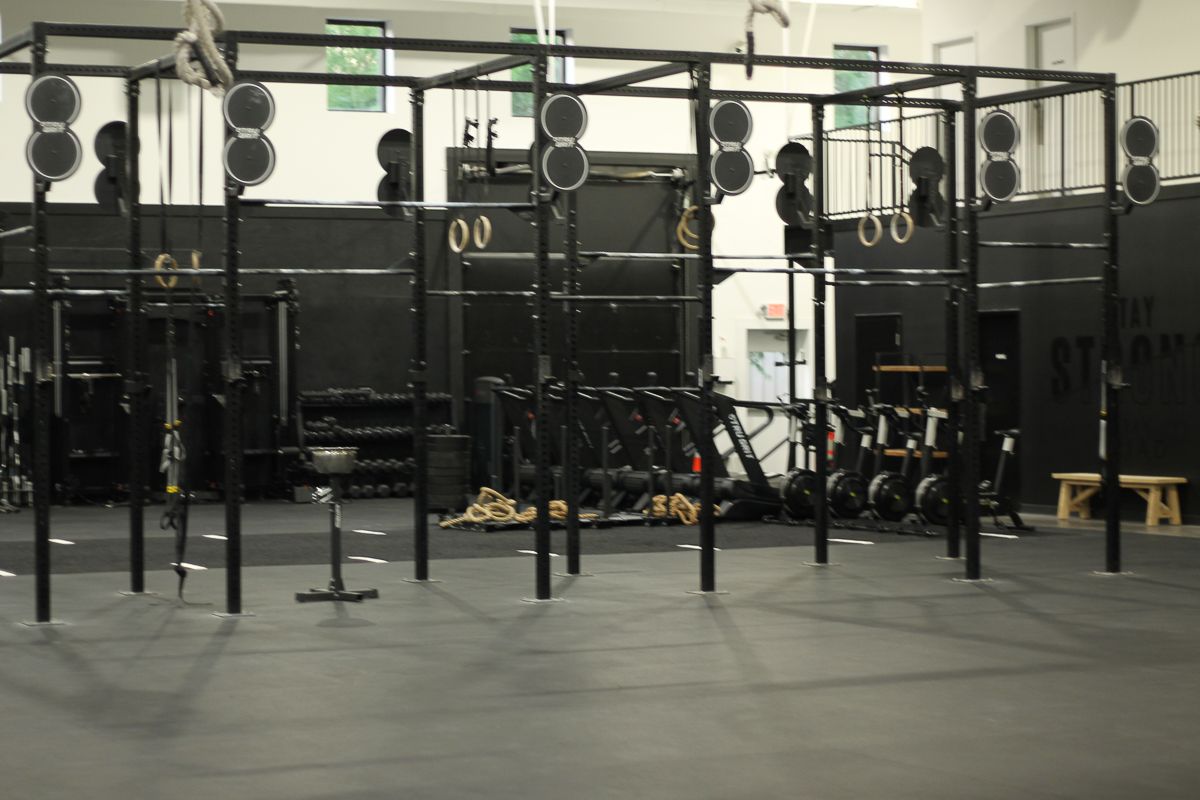 A black workout gym with various equipment, including rings, pull-up bars, and weight racks.