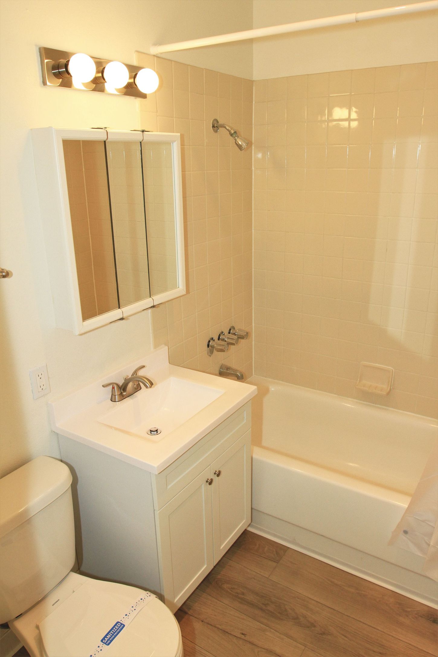 A bathroom with a toilet , sink , tub and mirror.