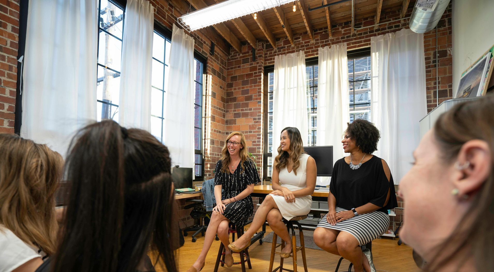 Three people seated in a bright loft space, speaking to an audience in a casual discussion panel.