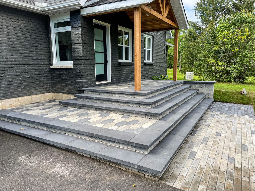 Brick house entrance with gray and tan brick steps and porch under a wooden canopy.