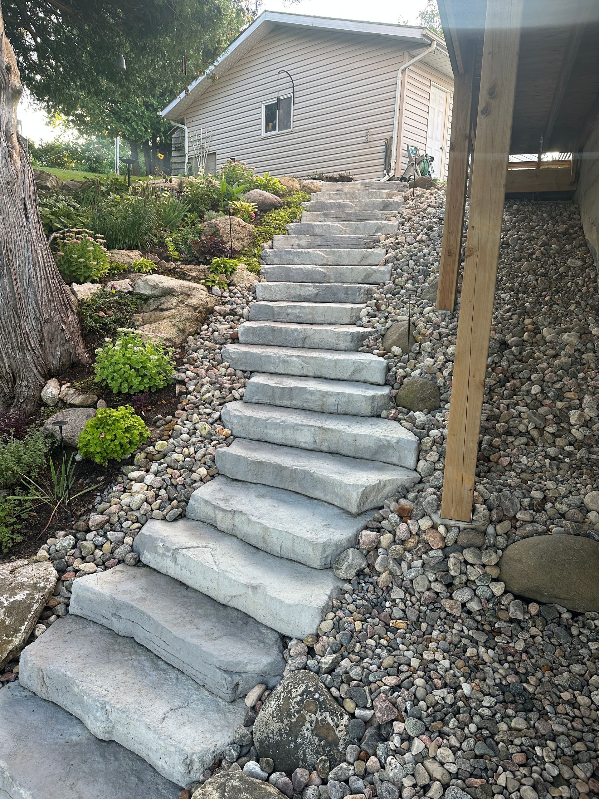 Stone steps leading up a hillside, beside a gravel path. A building is at the top.