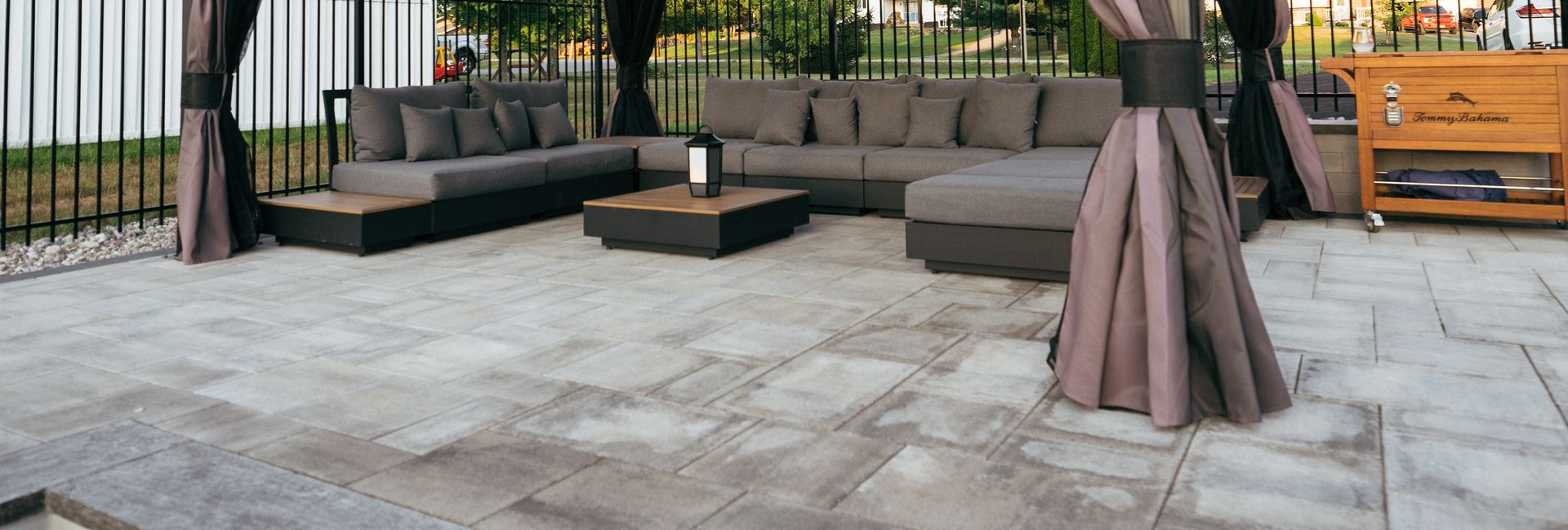 Modern backyard patio with a covered pavilion, comfortable outdoor seating, and stone pavers.