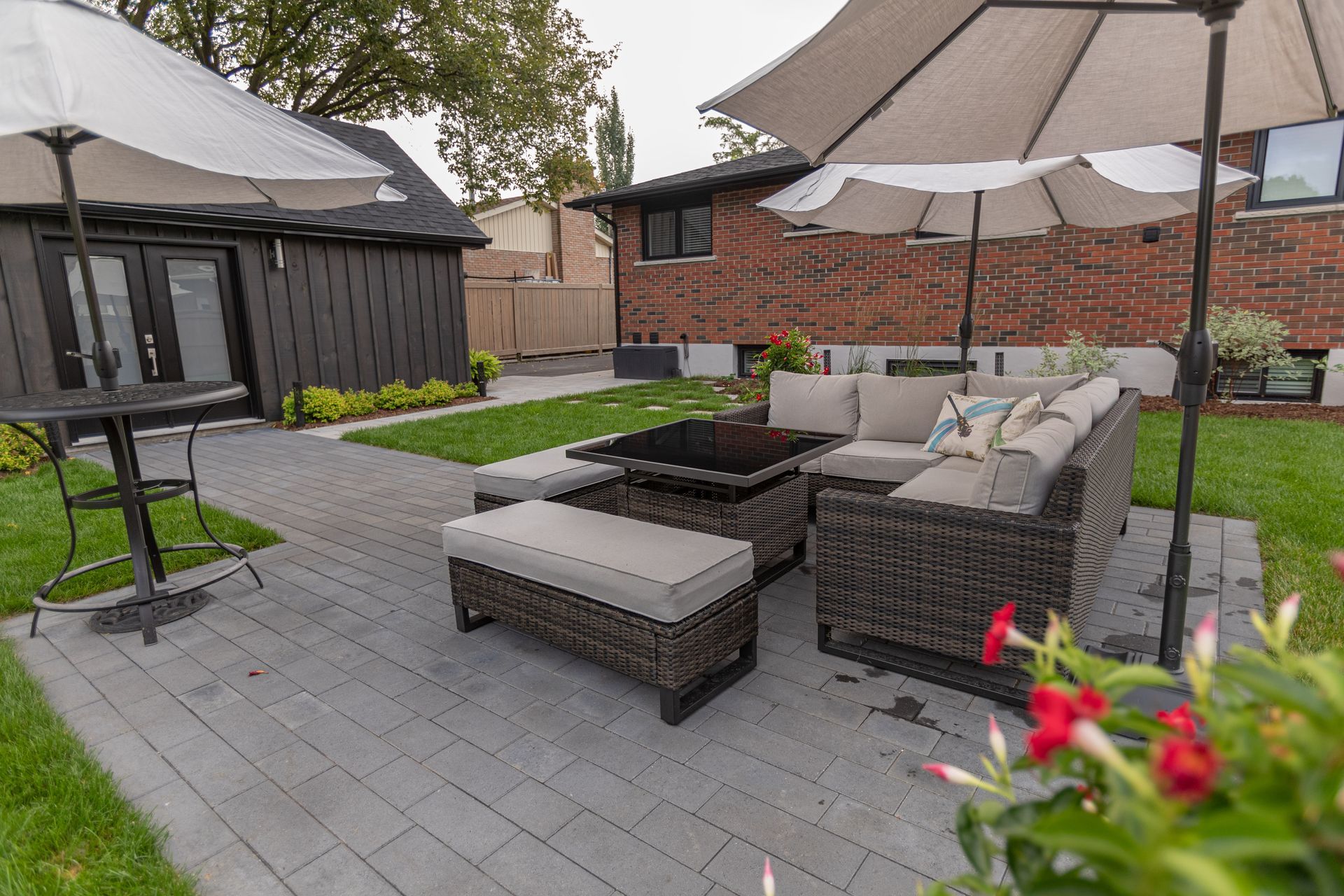 Outdoor patio with wicker furniture, umbrellas, and red flowers.