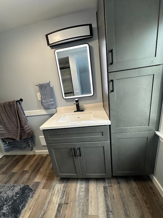 Gray bathroom with a vanity, cabinet, mirror, and towel rack.