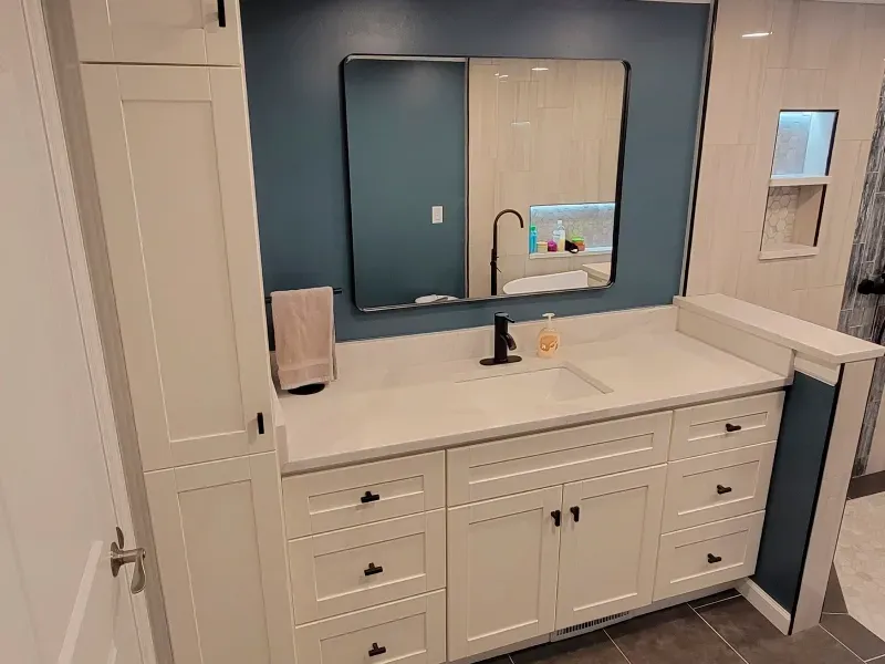 A bathroom with a sink , mirror and cabinets.