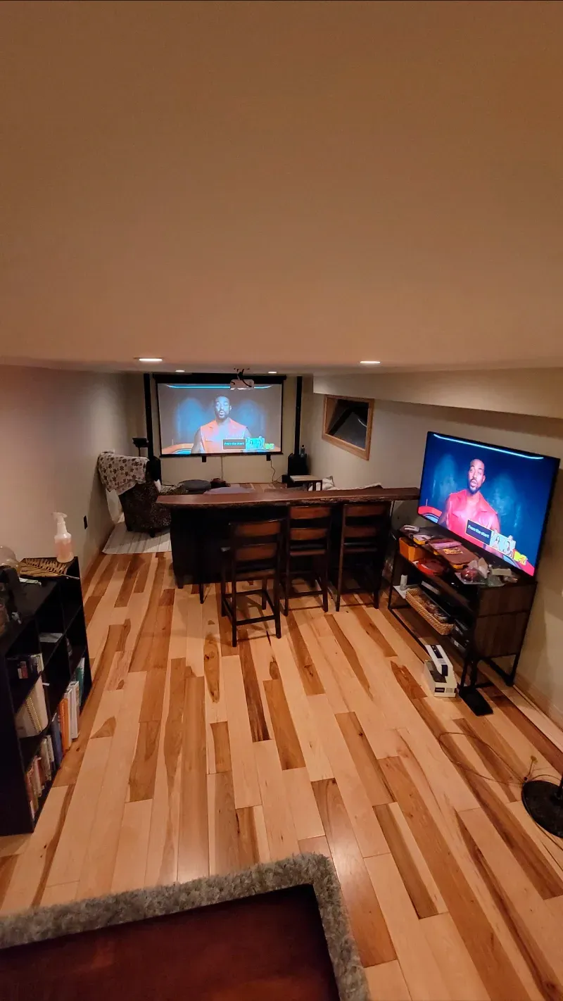 A living room with a projector screen and a flat screen tv.