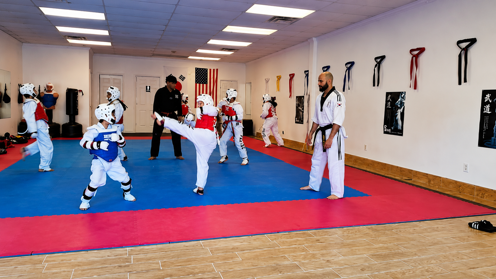 Two boys on a mat practicing Jiu-Jitsu. One boy is on top, giving a thumbs-up.