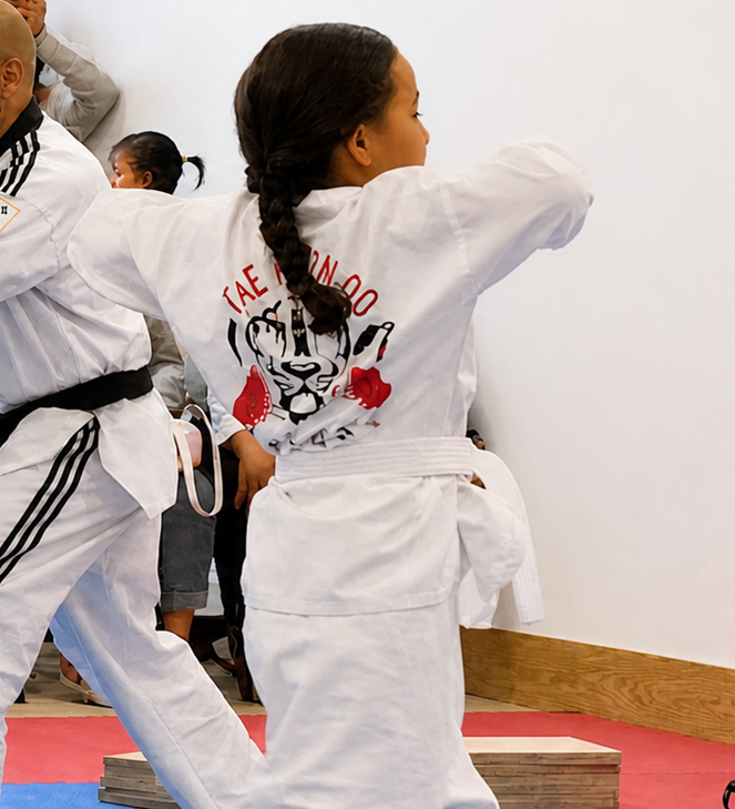 People practicing Brazilian Jiu-Jitsu. One person on the ground, another on top; two others grappling nearby. Black gis, indoor setting.