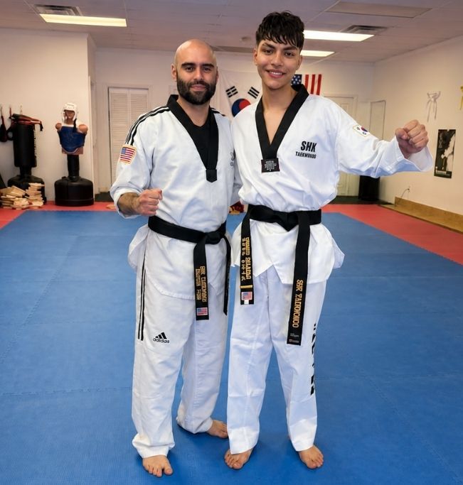 Two men grappling on a mat, one in blue, the other in black.