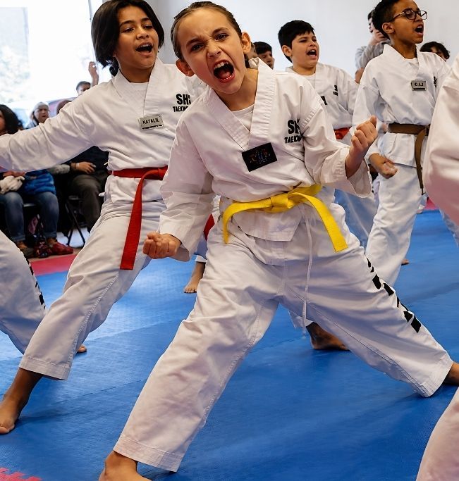 Two children grappling on a mat, one in a headlock.