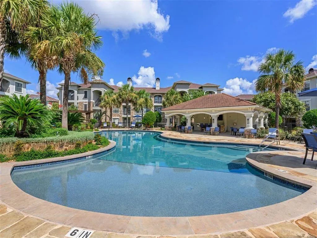 Resort-style swimming pool with a covered cabana and lounge seating at a multifamily property.