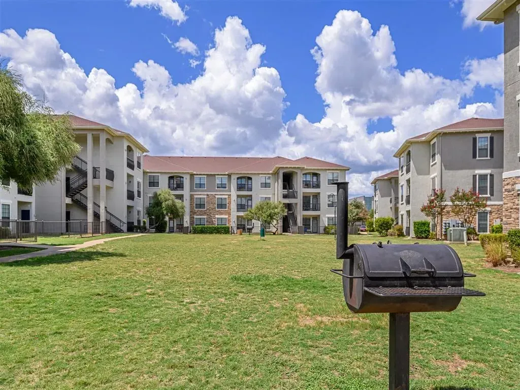 Apartment buildings with a BBQ grill in the foreground.