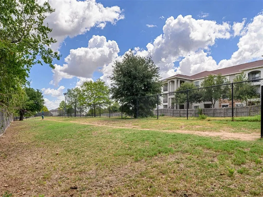 Fenced dog park area with apartment building in the background.