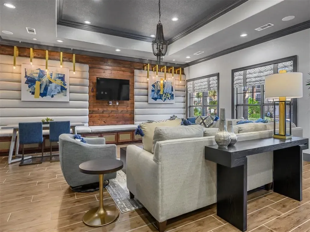 Interior lounge area with sofas, chairs, and a TV mounted on a wood-paneled wall.