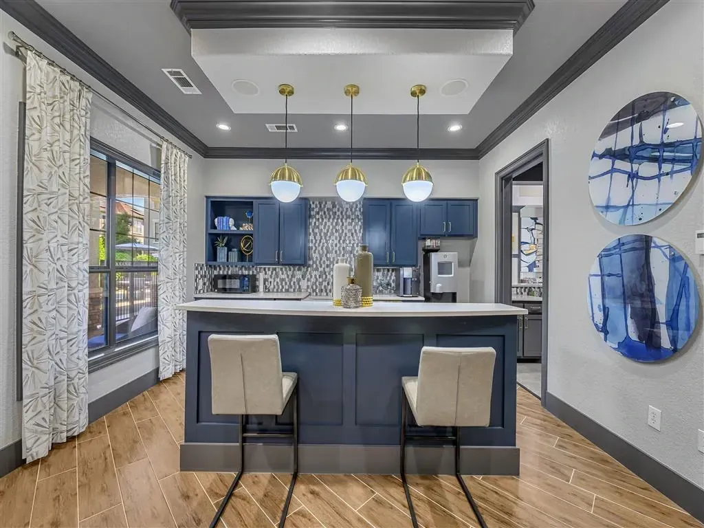 Community kitchen area with navy blue cabinets, a large island with seating, and modern decor.