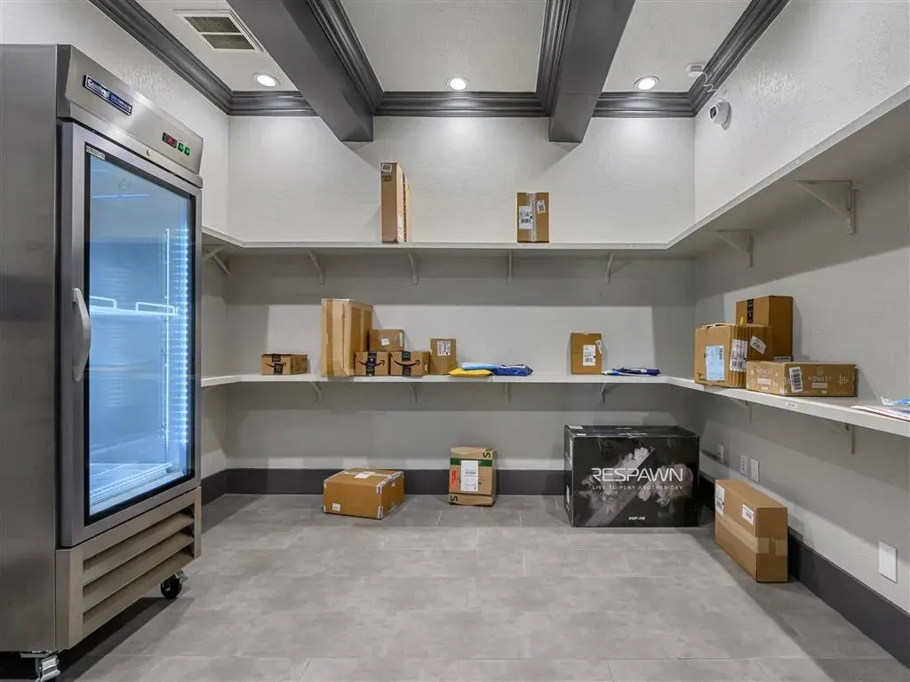 Package room with a commercial refrigerator and shelves stocked with boxes.
