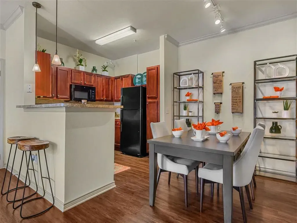 Modern kitchen and dining area with dark wood cabinets, black appliances, and a grey dining set.