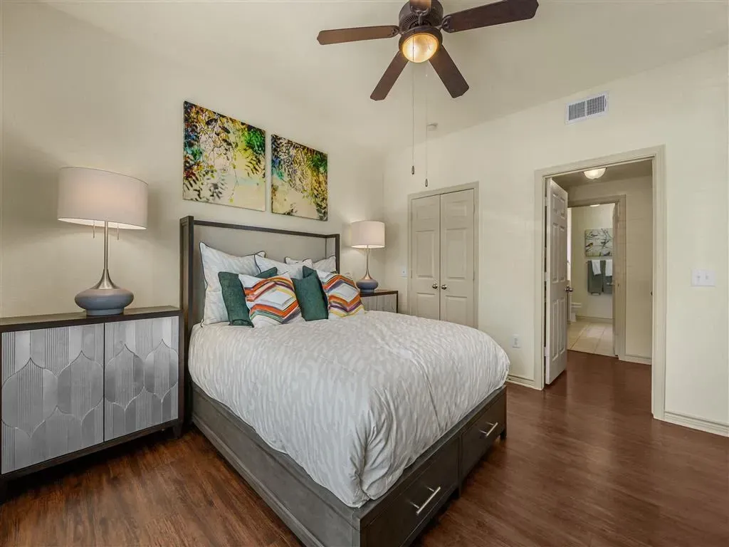 Bedroom with a king-size bed, nightstands, dresser, and ceiling fan.
