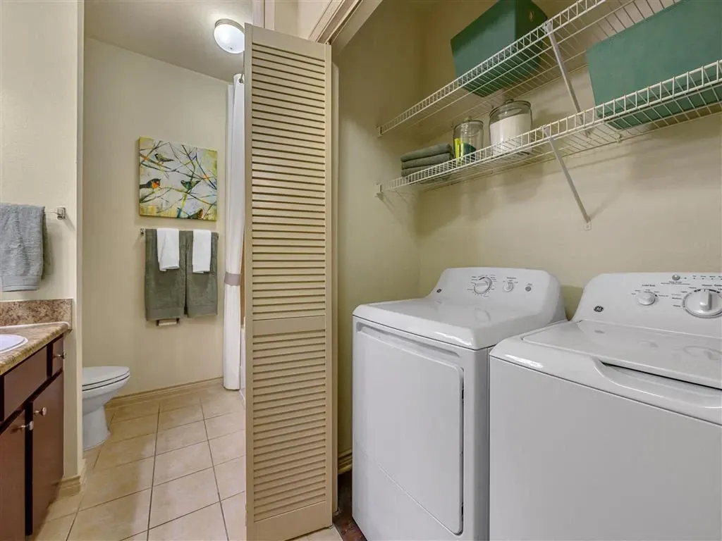 Bathroom with toilet, vanity, and laundry area with washer and dryer.