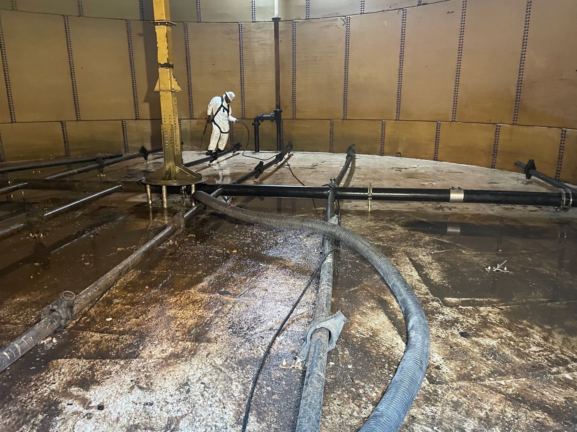An Elk Environmental Services crew members uses a power washer to clean a clarifying tank. 