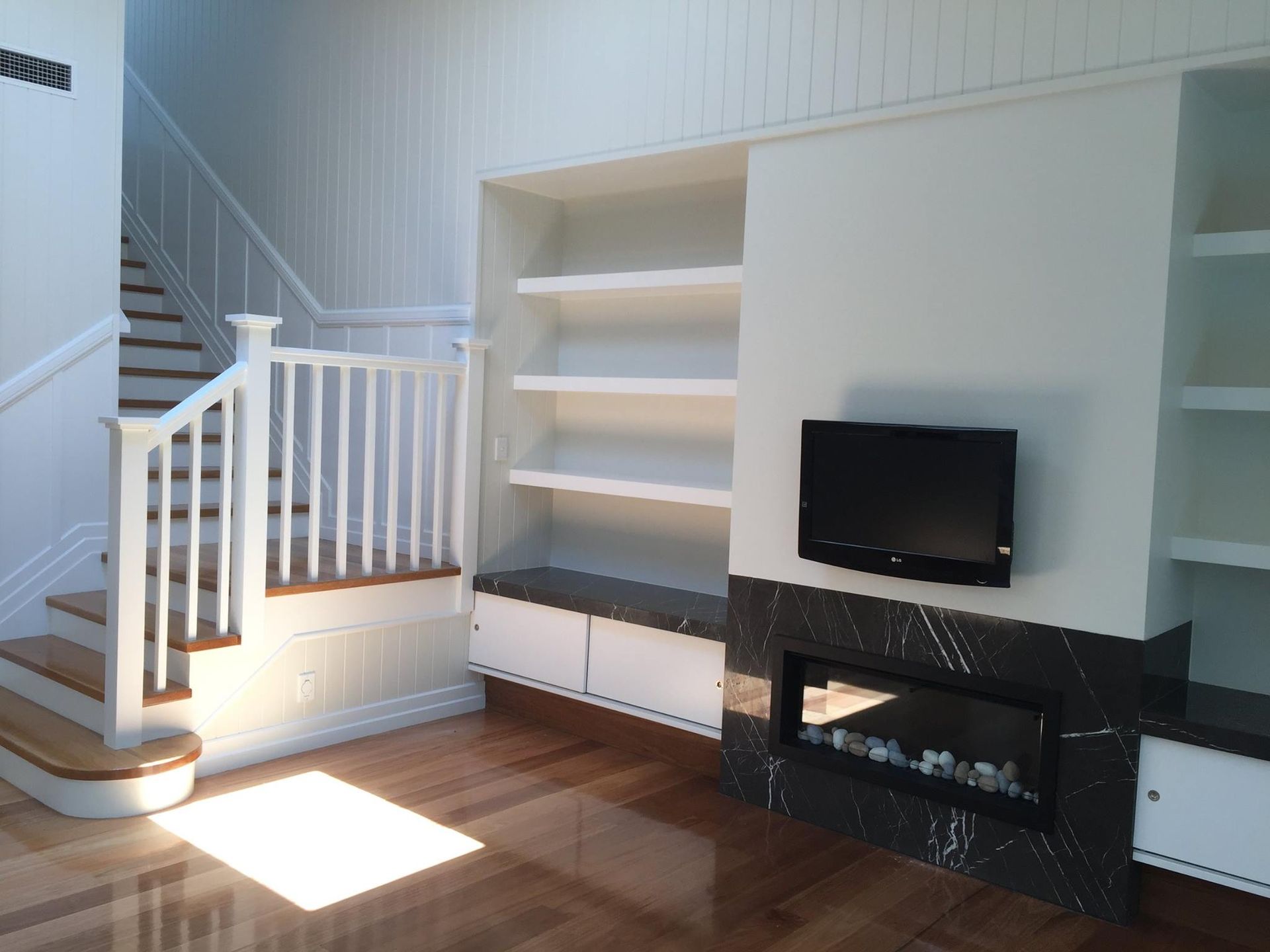 A Living Room With Stairs A Fireplace And A Flat Screen Tv — North Coast Cabinets In Tweed Heads, NSW