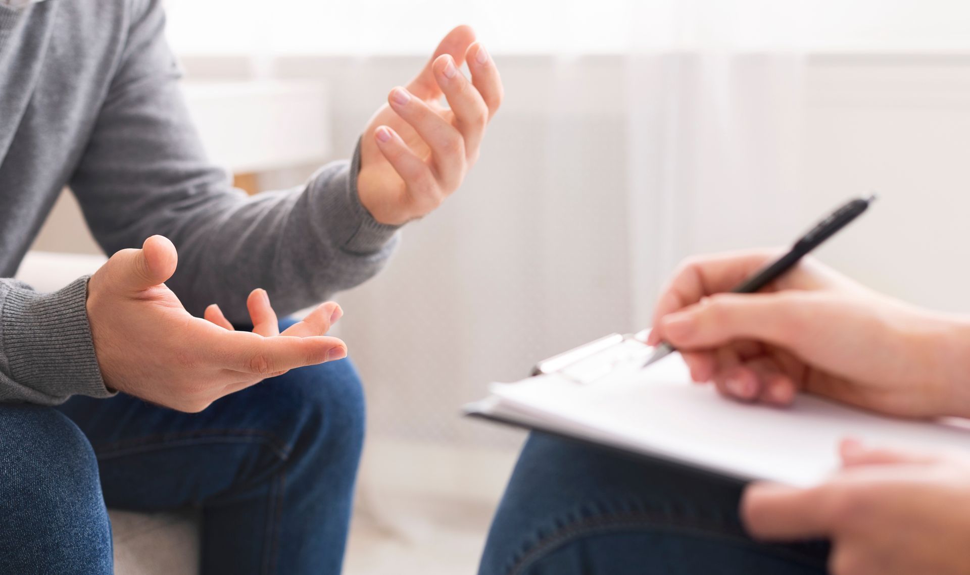 Counselor and client in discussion, with notebook and pen during a therapy session Counselor and client in discussion, with notebook and pen during a therapy session