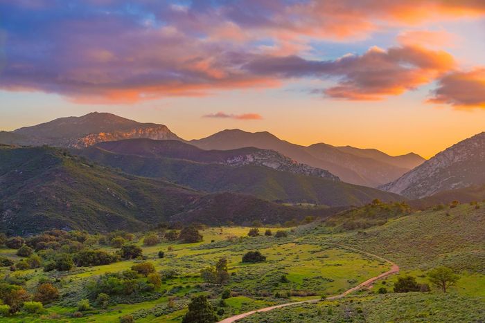 Mountains in Sunset — Laguna Hills, CA — Dr. Debra A Hill, MD Mountains at sunset with golden and purple skies over green valleys.