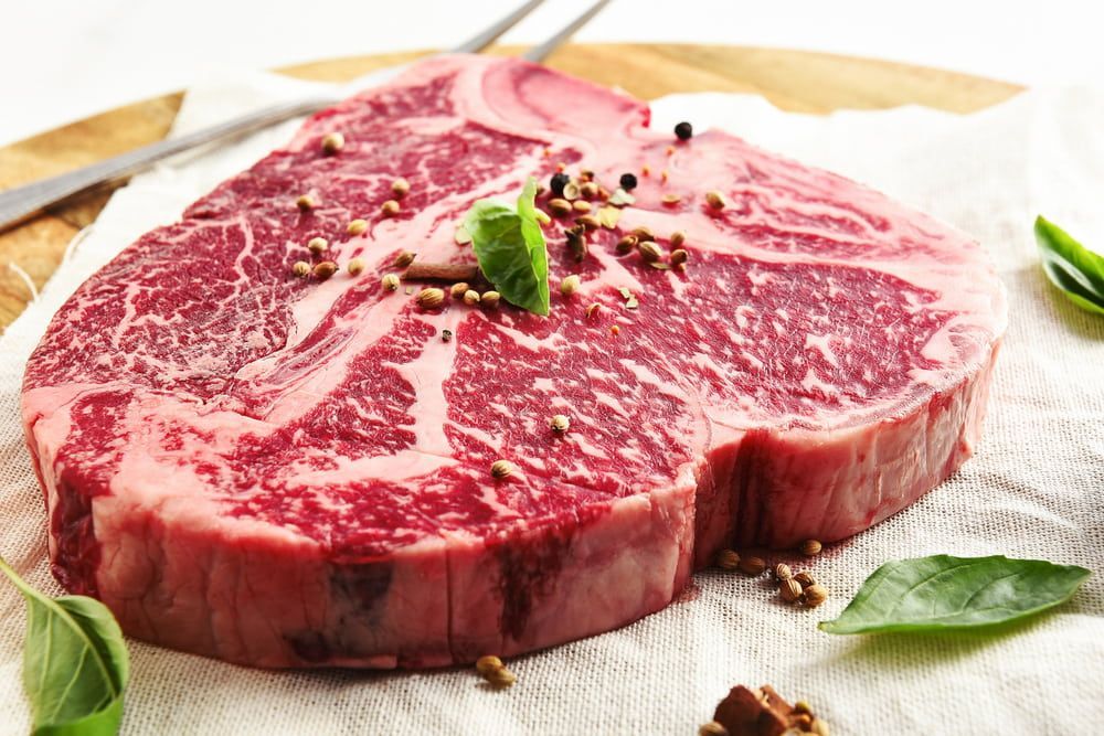 A Large Piece Of Raw Steak Is Sitting On A Cutting Board — Wattle Butchery In Cootamundra, NSW