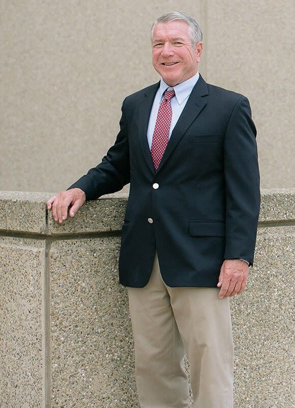 A man in a suit and tie leans against a wall