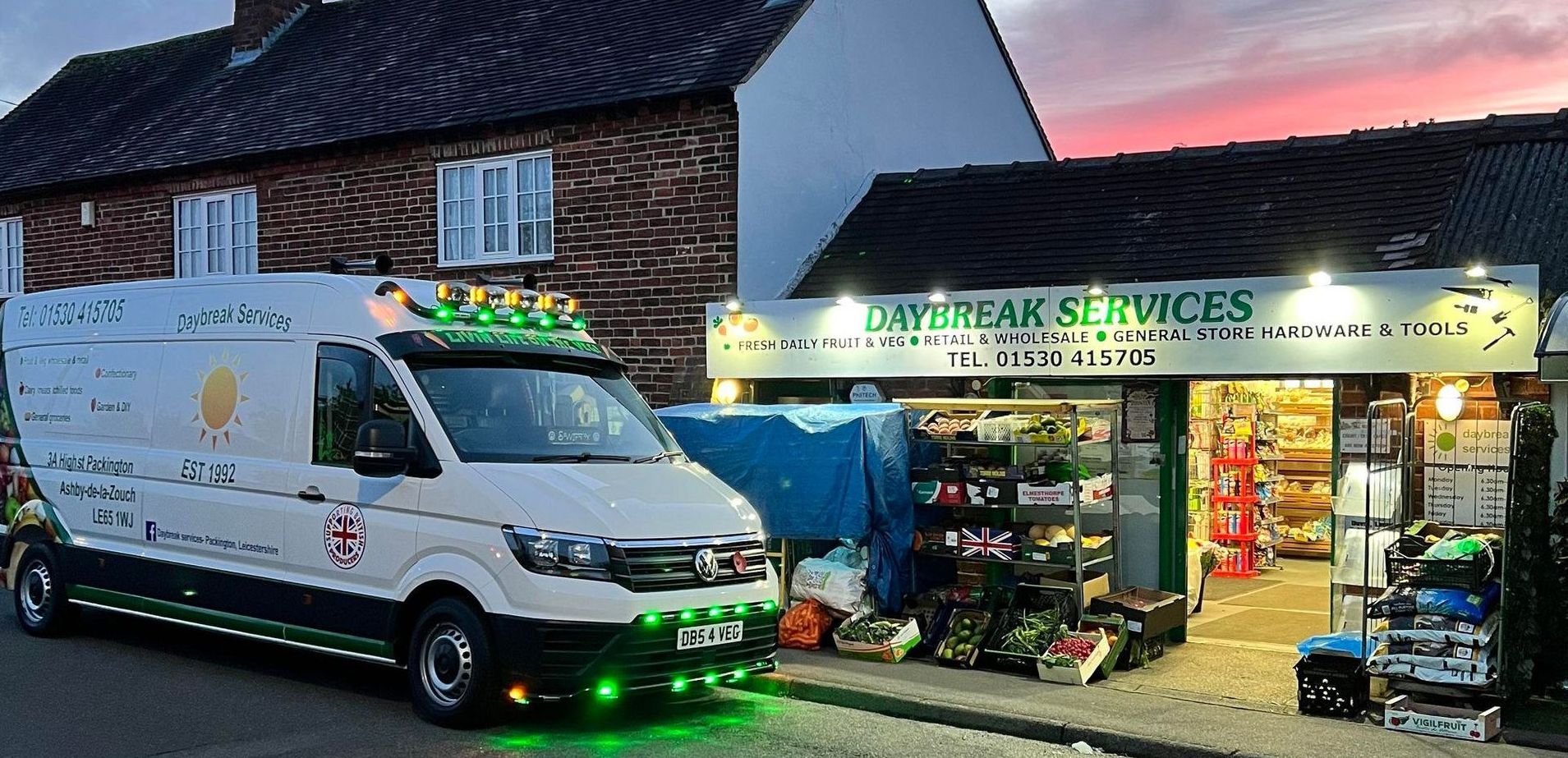 Delivery van parked outside a brightly lit hardware store at dusk