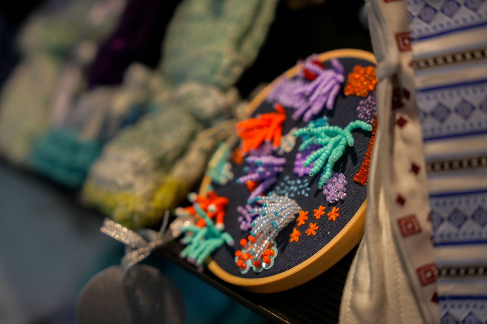 Colorful embroidered hand fan with floral patterns displayed among woven textiles