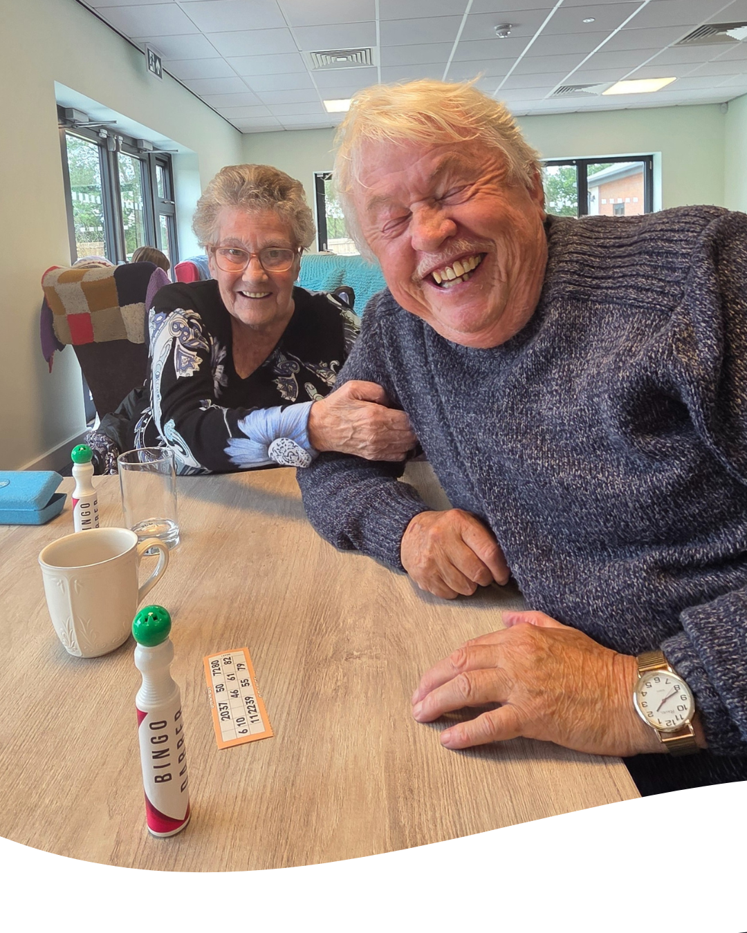 Two people smiling at a table with game pieces in a bright room