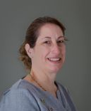 Portrait of a smiling person in a gray shirt against a plain gray background