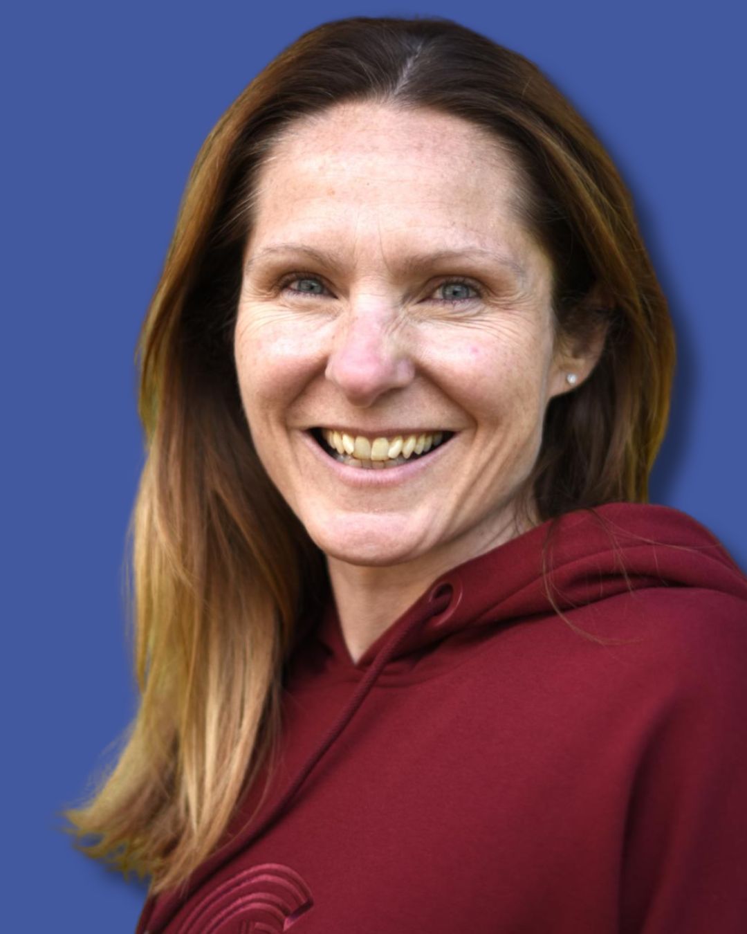 Smiling person in a maroon hoodie against a blue background