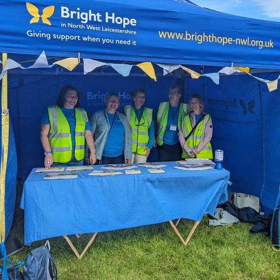 Bright Hope charity volunteers at a blue event tent with a table and leaflets outdoors