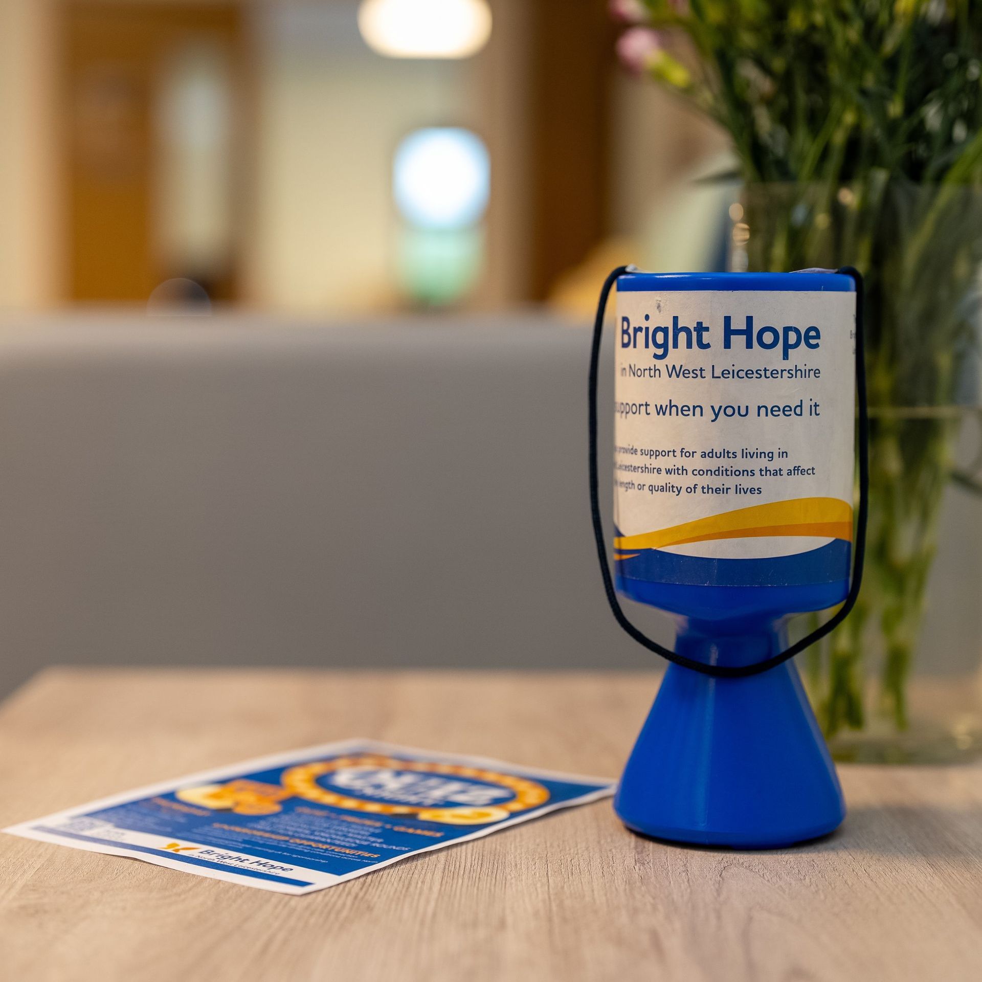 Blue “Bright Hope” donation cup on a table beside a flyer in a waiting room