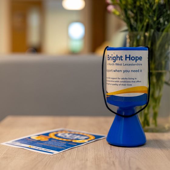 Blue “Bright Hope” table tent on a wooden table in a blurred office or lobby setting.