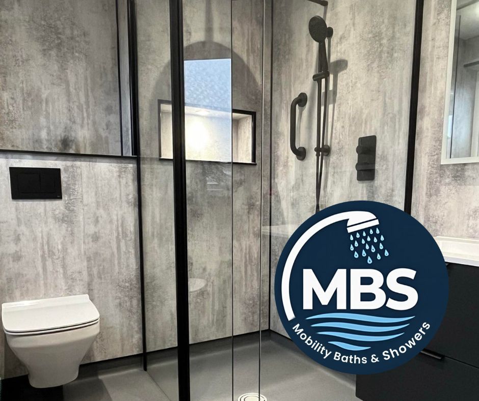 Modern gray-tiled bathroom with glass shower, wall-mounted toilet, and MBS Mobility Baths & Showers logo