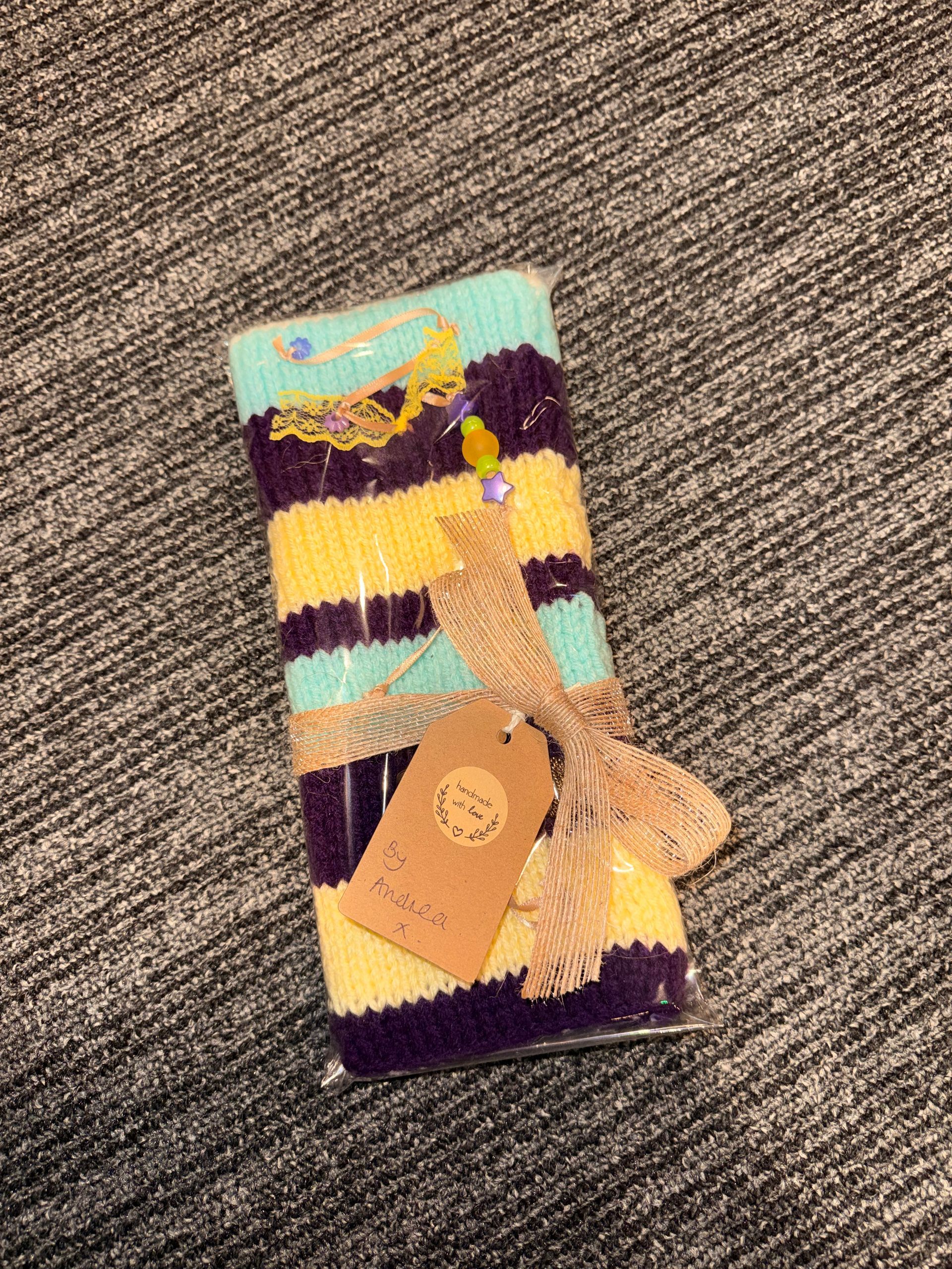 Small blue-and-red packaged item with a tan ribbon on a carpeted floor