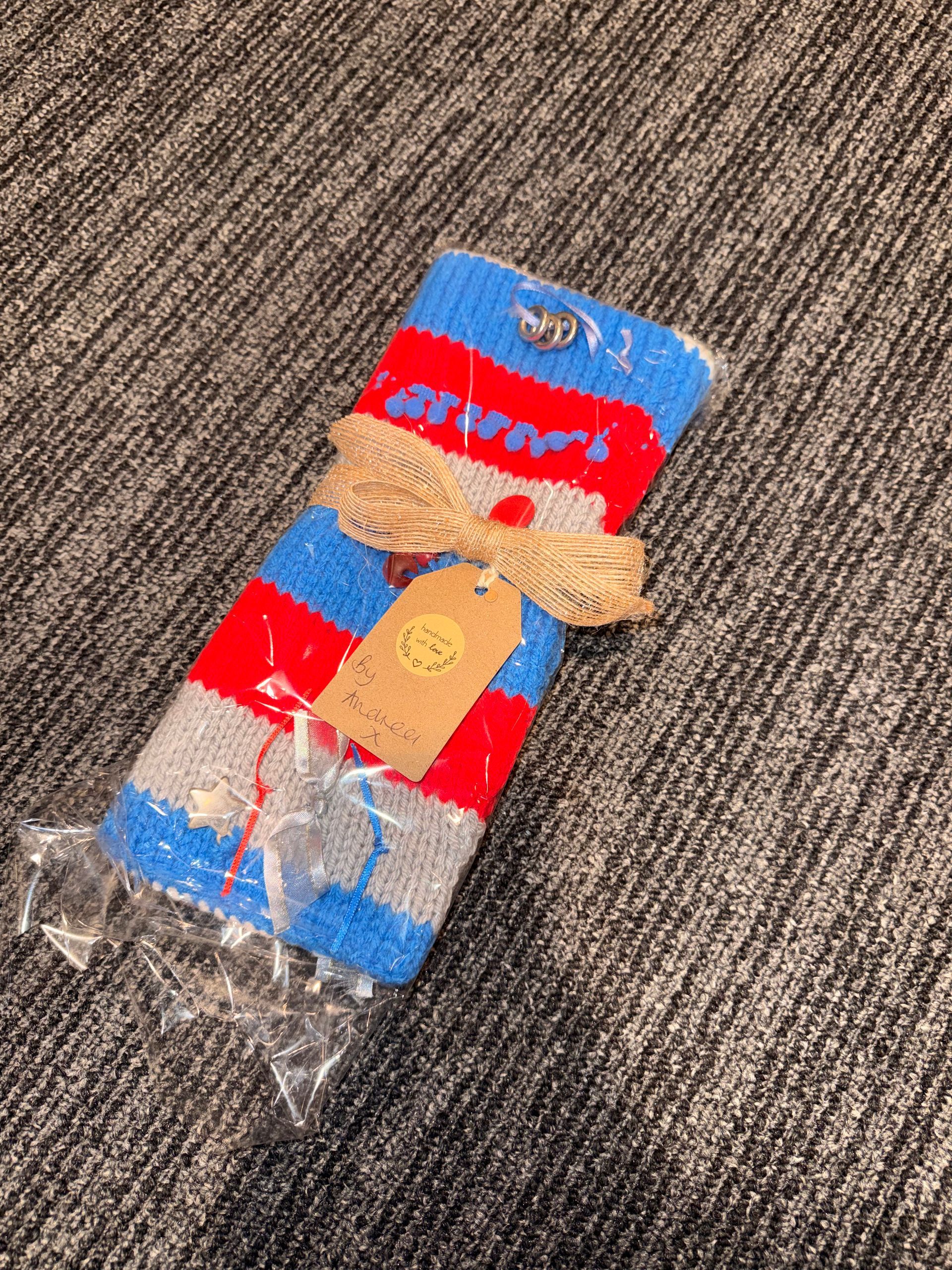 Small blue-and-red packaged item with a tan ribbon on a carpeted floor