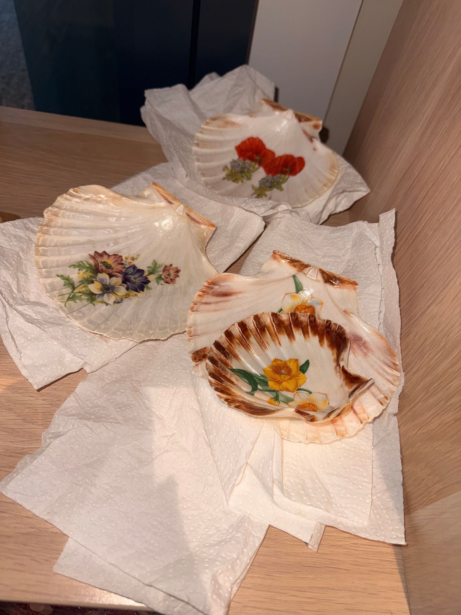 Three decorative ceramic dishes wrapped in paper on a wooden surface.