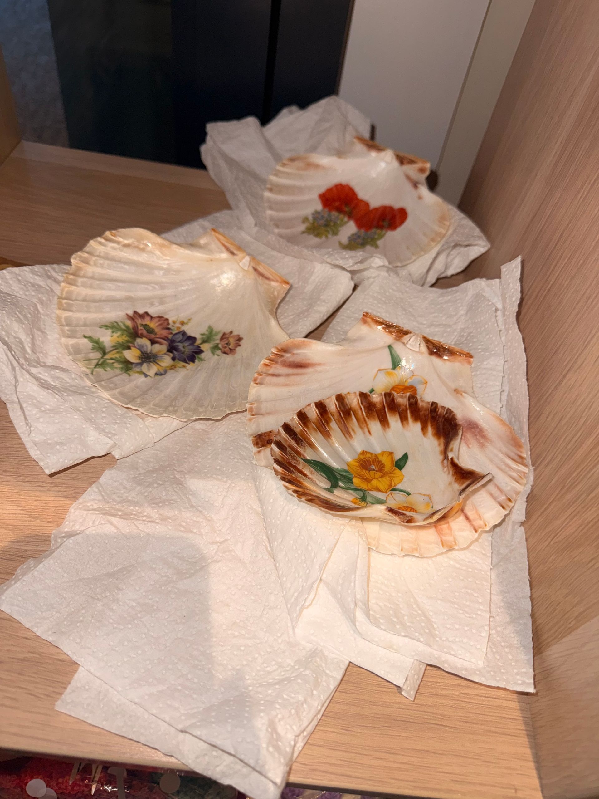 Three decorative ceramic dishes wrapped in paper on a wooden surface.