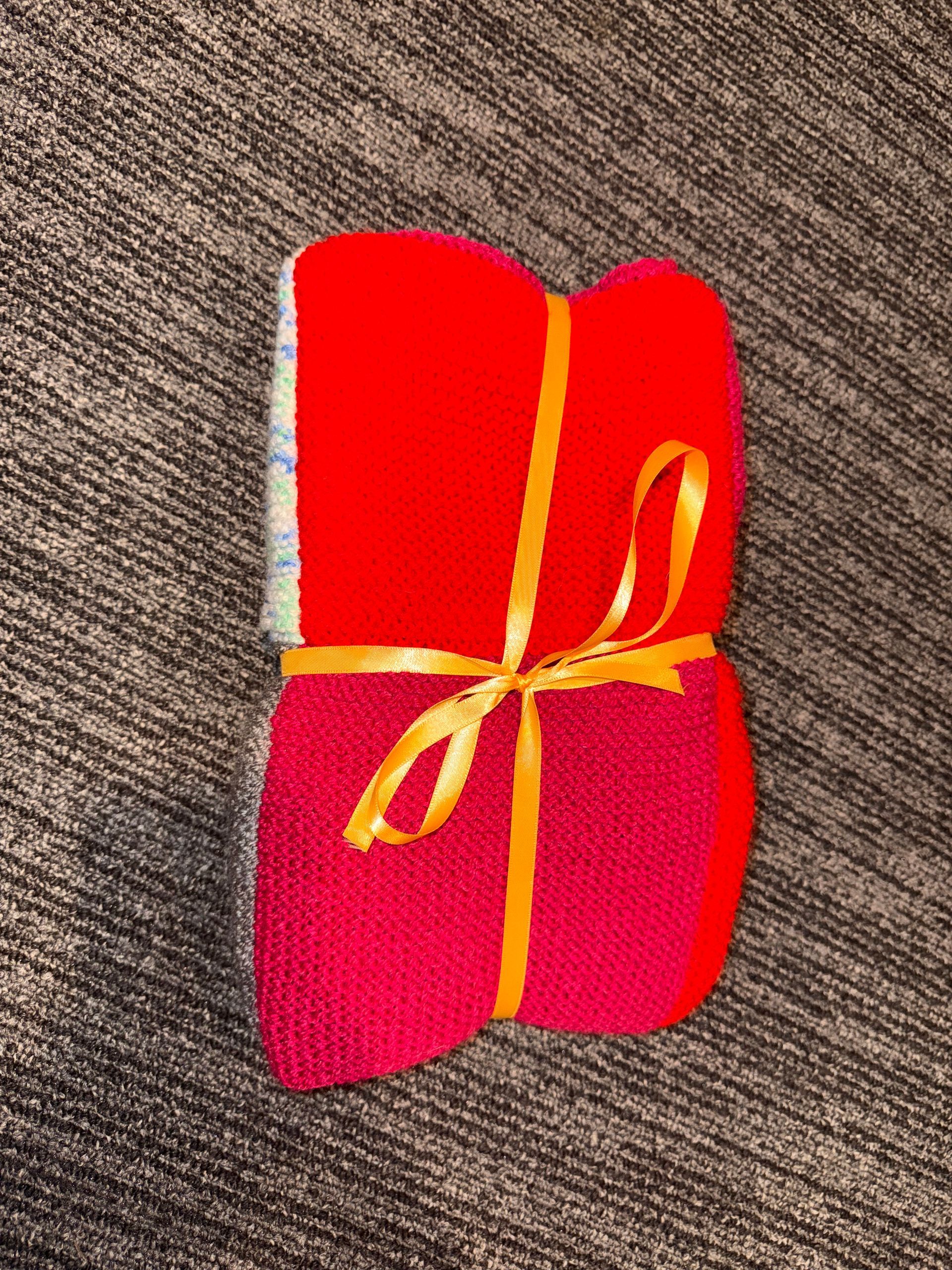 Red rolled blanket or towel tied with yellow ribbon on a brown textured surface