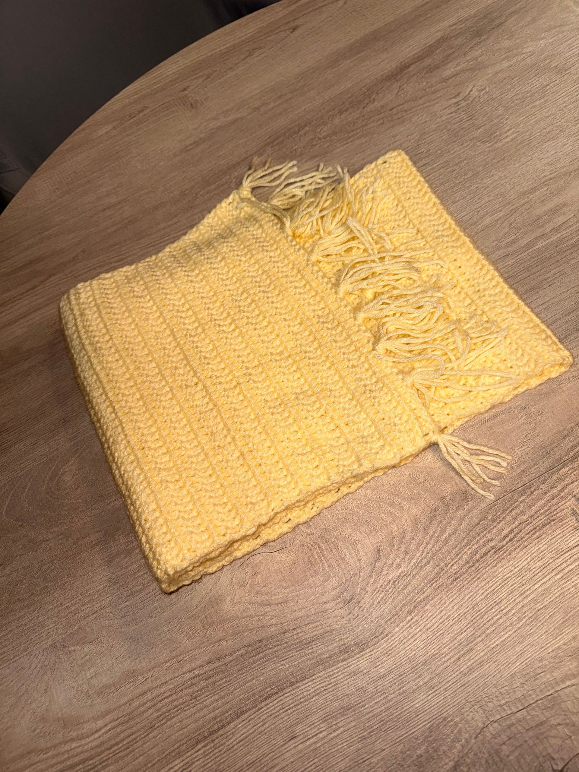 Yellow woven fabric square lying on a brown couch, with a frayed edge at the top.