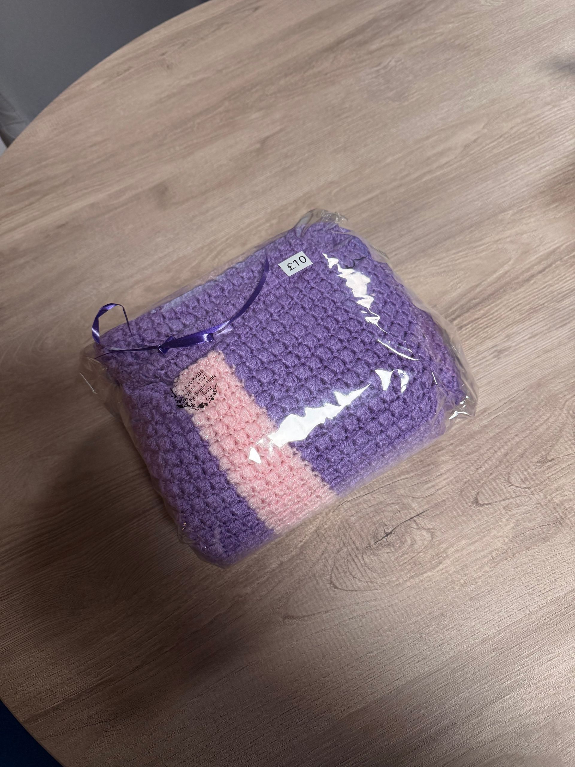 Small purple woven pouch with a pink stripe on a wooden surface.