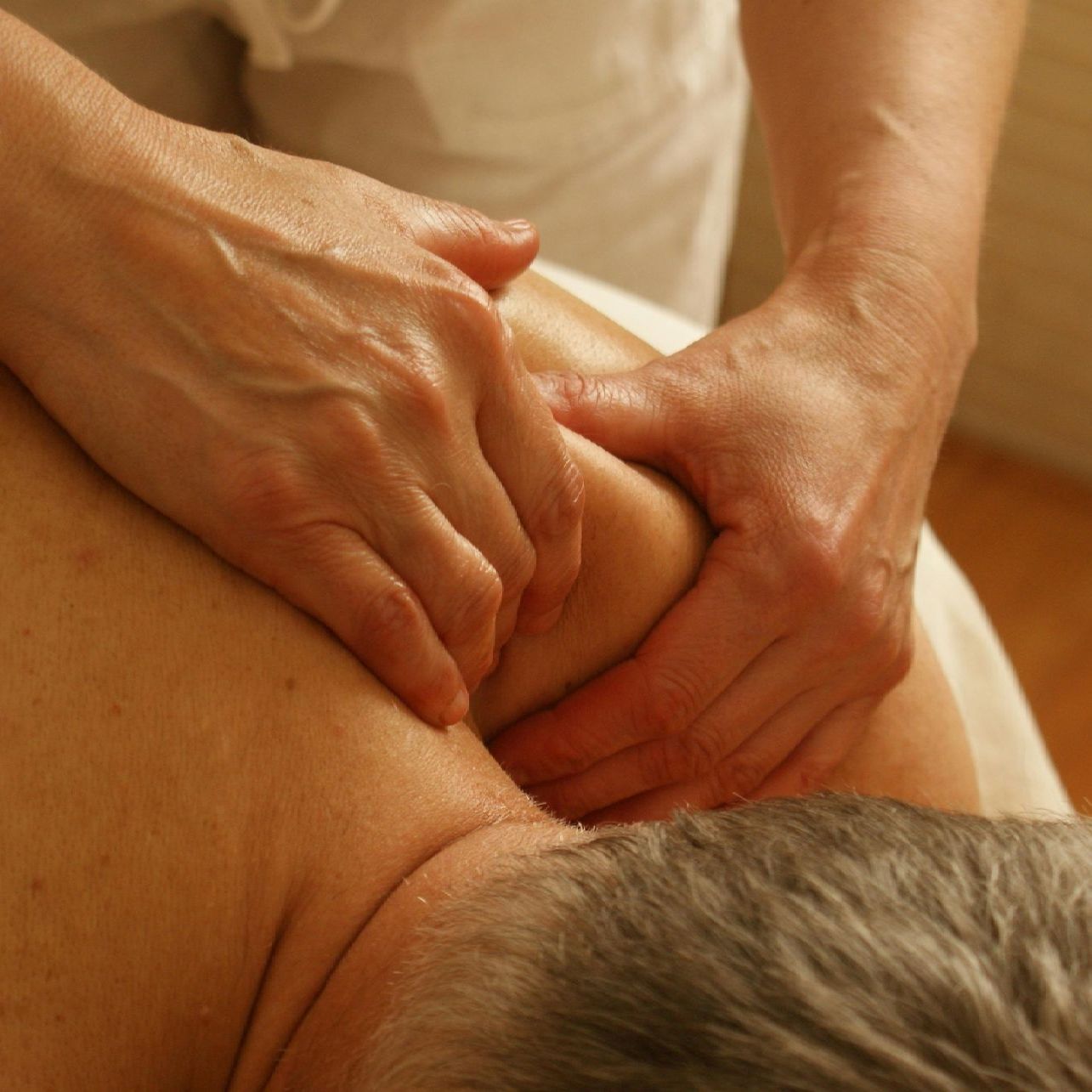 Hands giving a shoulder massage in warm light