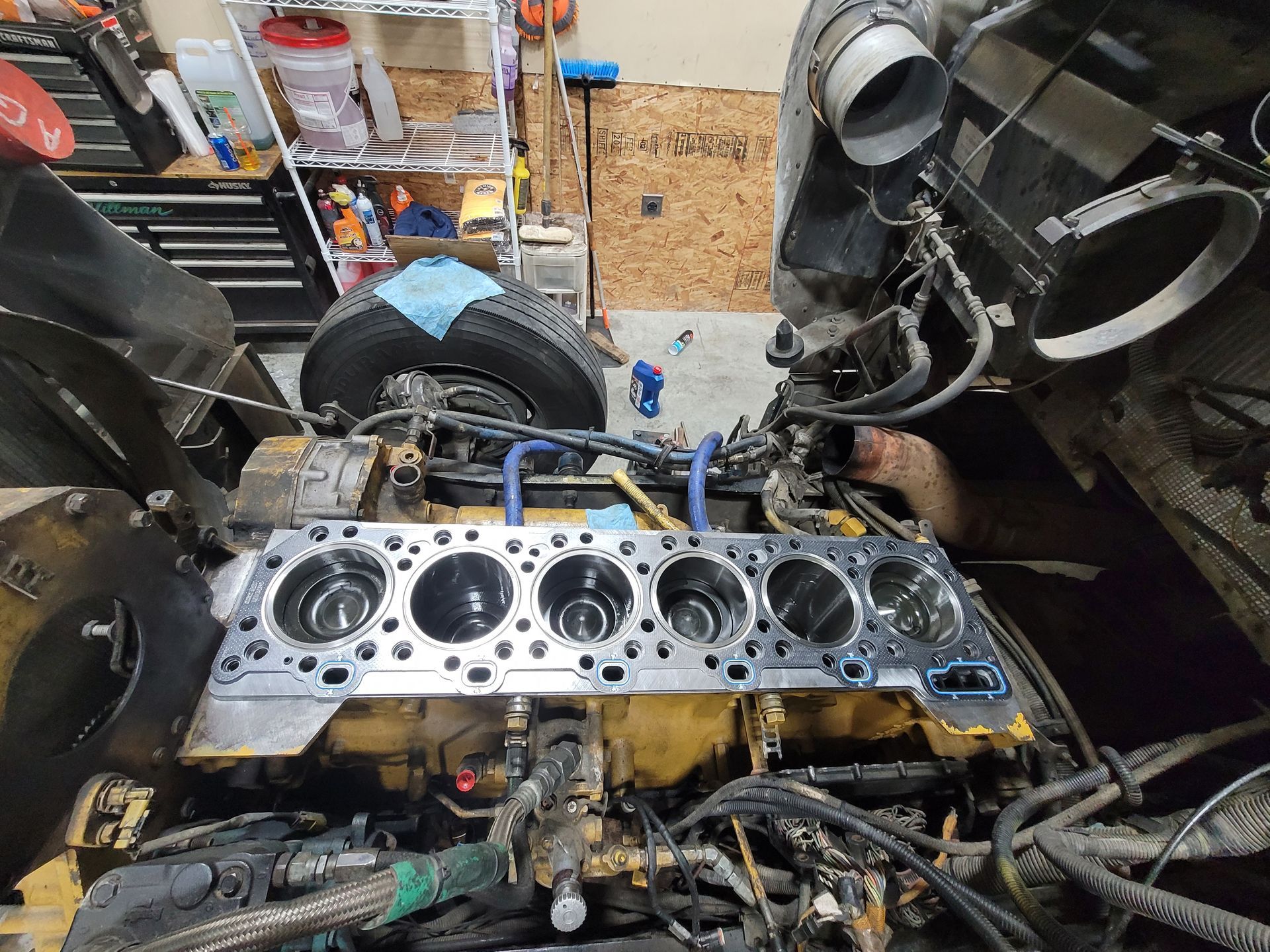A man is working on a truck engine in a garage.