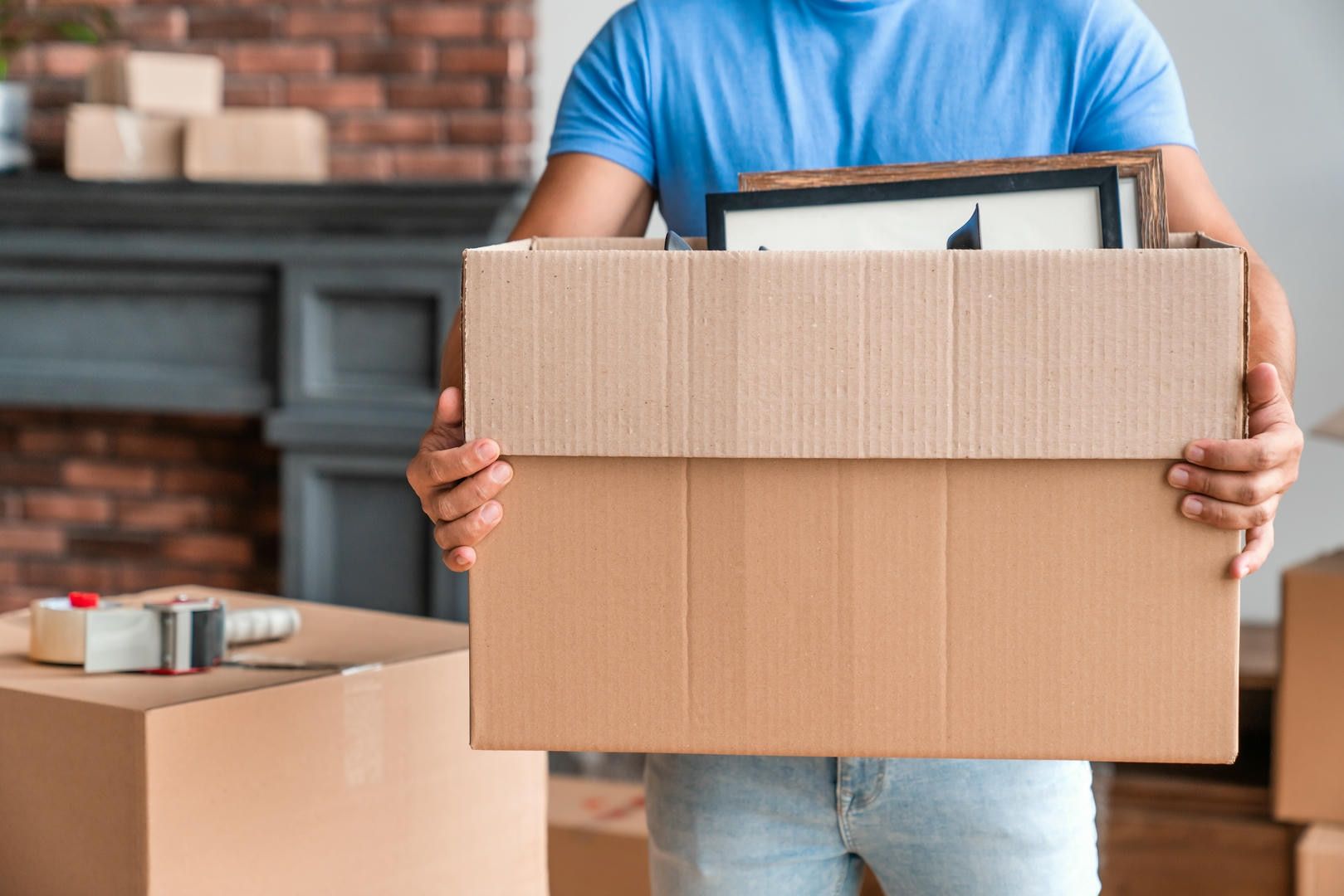 A man is holding a cardboard box with pictures in it.