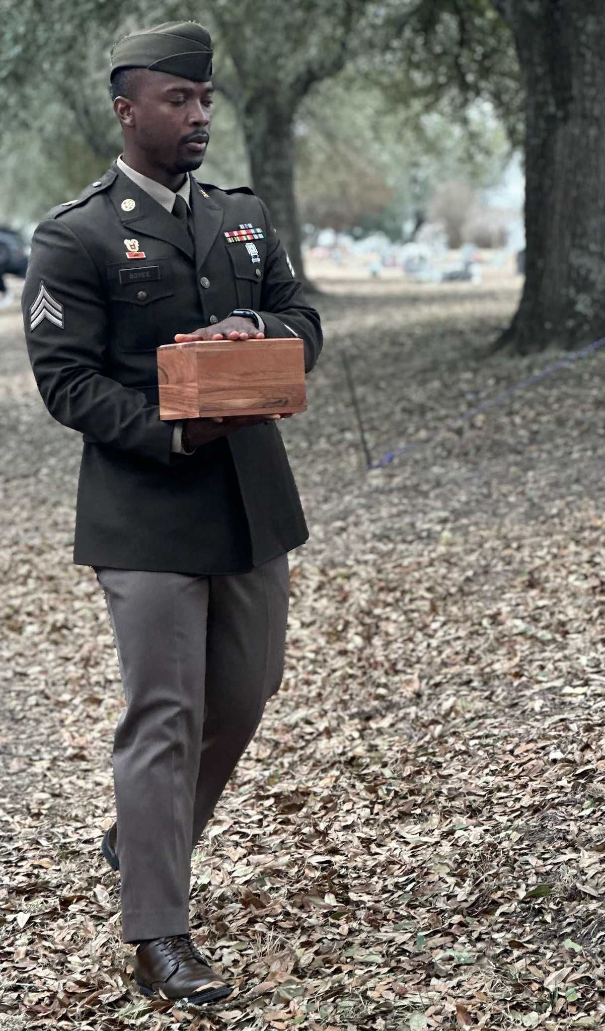A man in a military uniform is holding an american flag in his hands.
