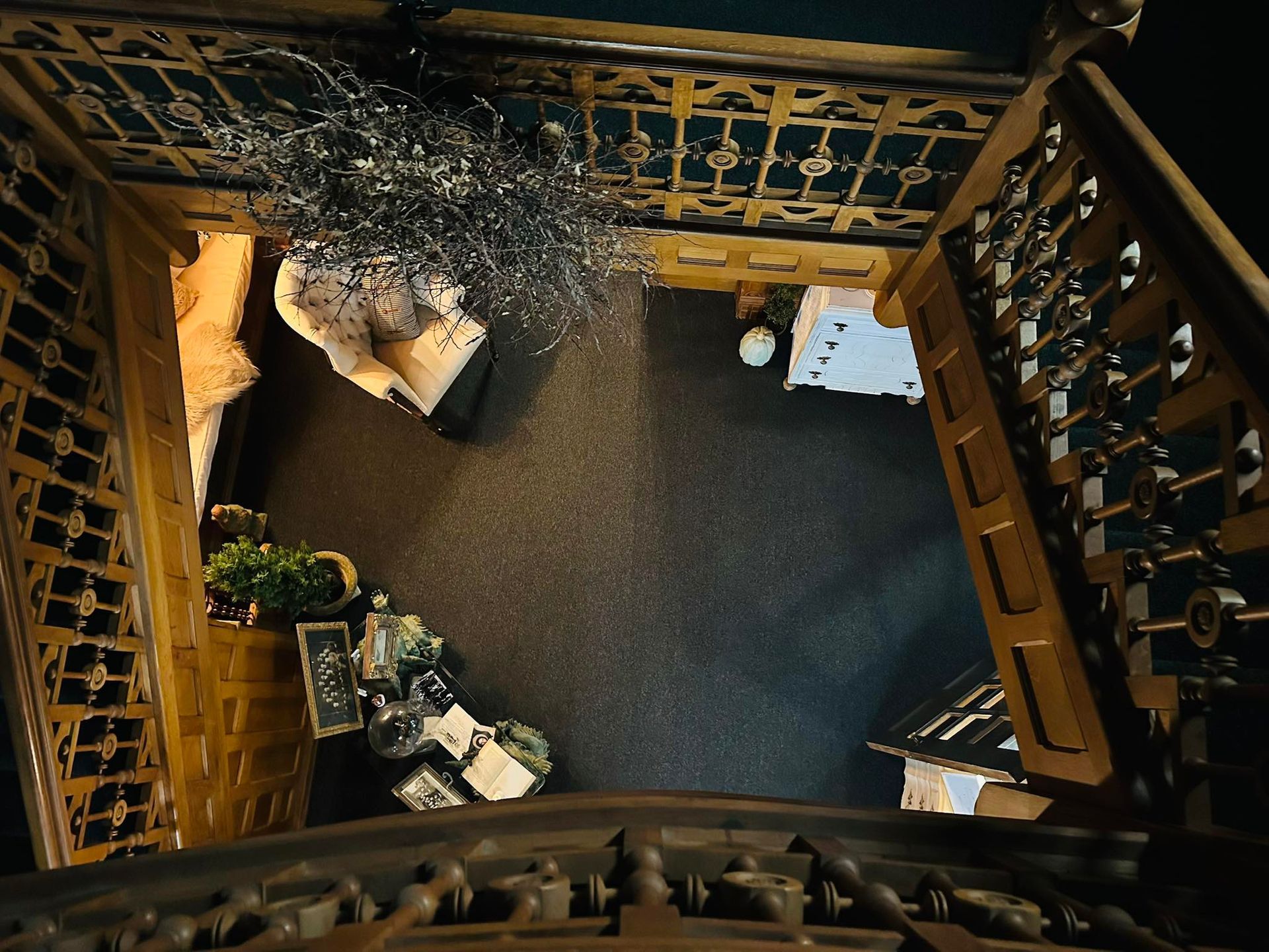 Overhead view of a detailed wooden staircase leading down to a hallway with a rug and furniture.